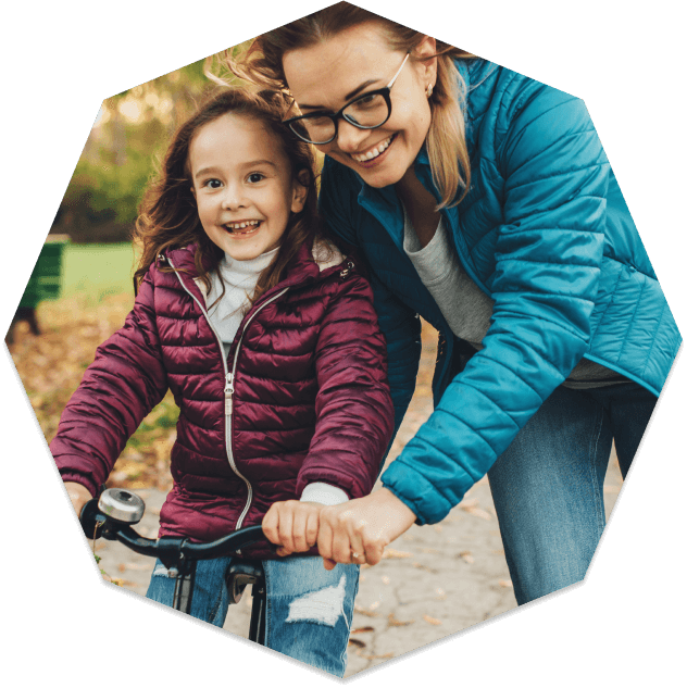 Mother in glasses teaching her daughter how to ride a bike